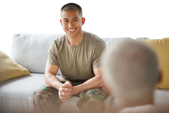 A man seated on a sofa, talking with someone